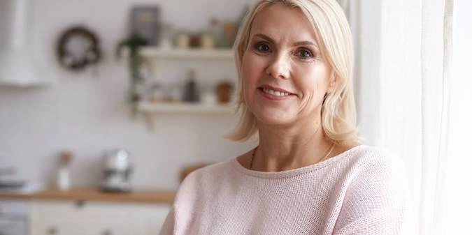 A middle aged woman smiling confidently, reflecting natural vitality and optimized feminine health balance